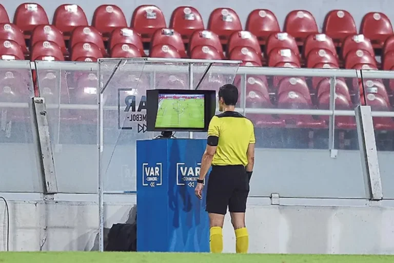 Árbitro revisando el VAR en un partido de fútbol profesional.